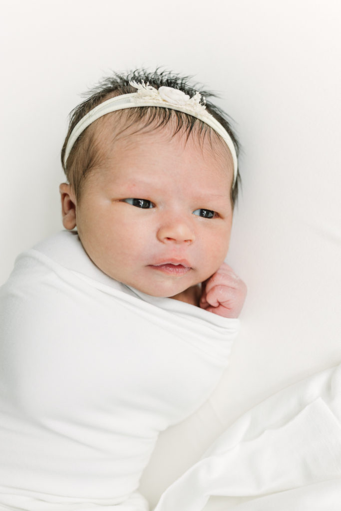 Newborn baby girl with her eyes open  during photo session.