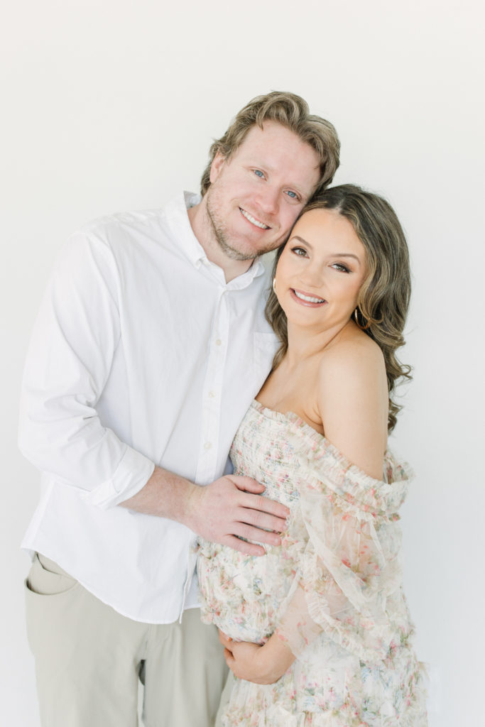 Expecting Mom and Dad smile at camera during maternity session in Atlanta Photography Studio. Spencer Livingston Photography is an Atlanta Newborn and Family Photographer.