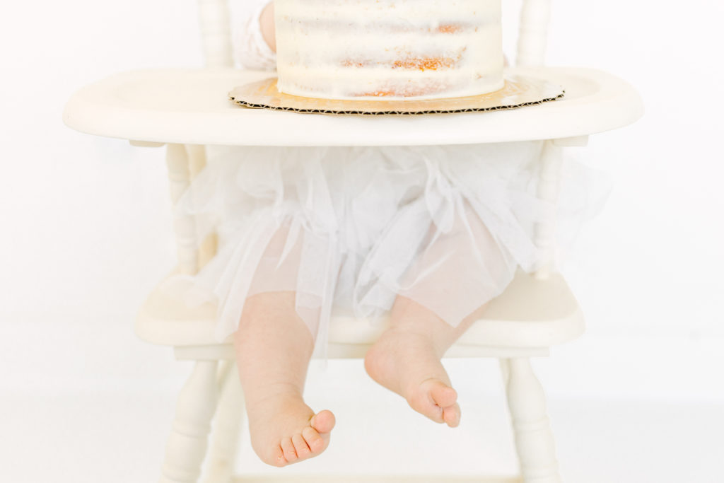 Baby eats cake in antique highchair for her 1st birthday session at Atlanta Photographer's Studio