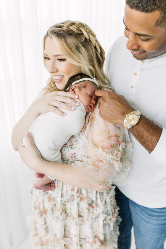 Mom and dad smile at their baby girl during her atlanta studio newborn photography session.