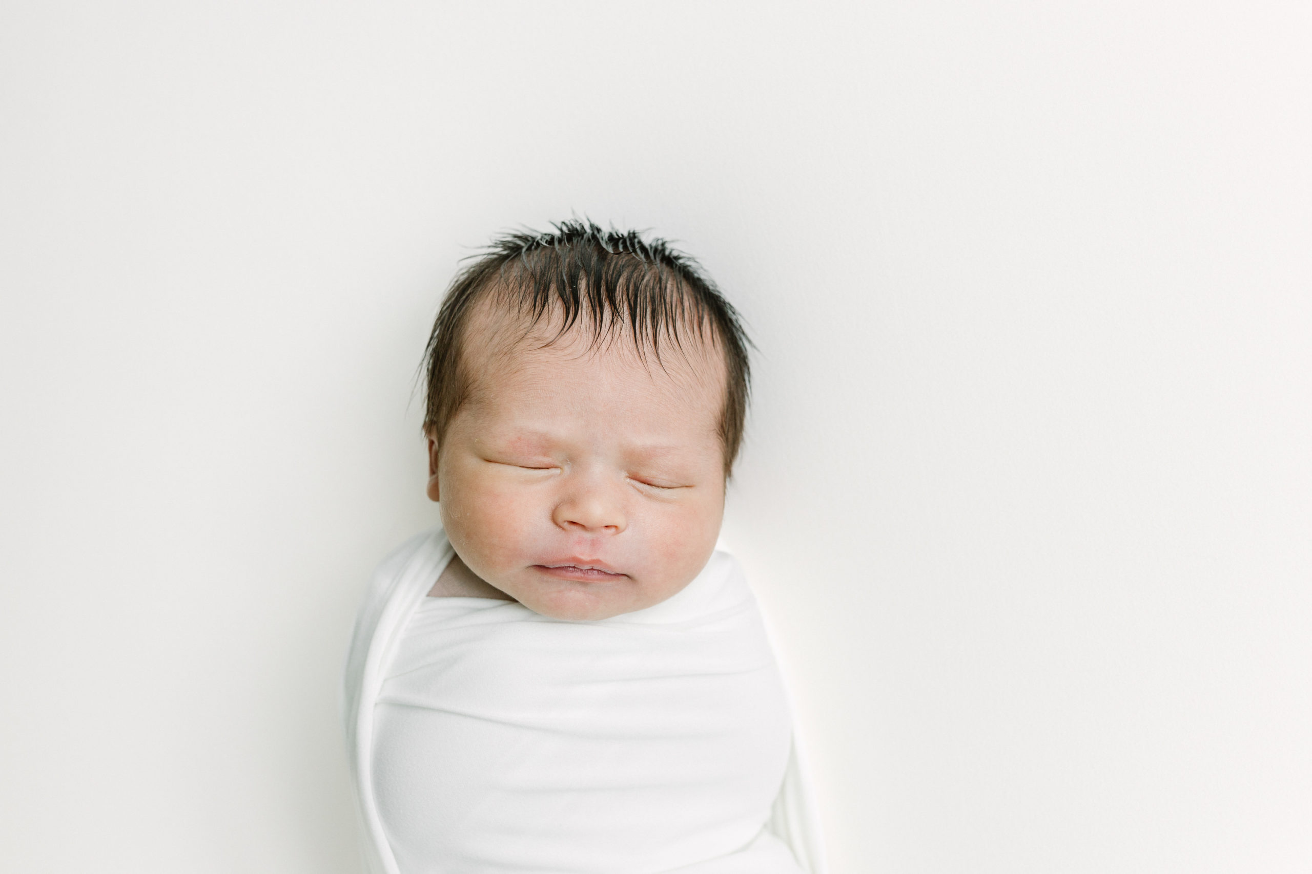 Newborn baby lies peacefully on photography beanbag. 