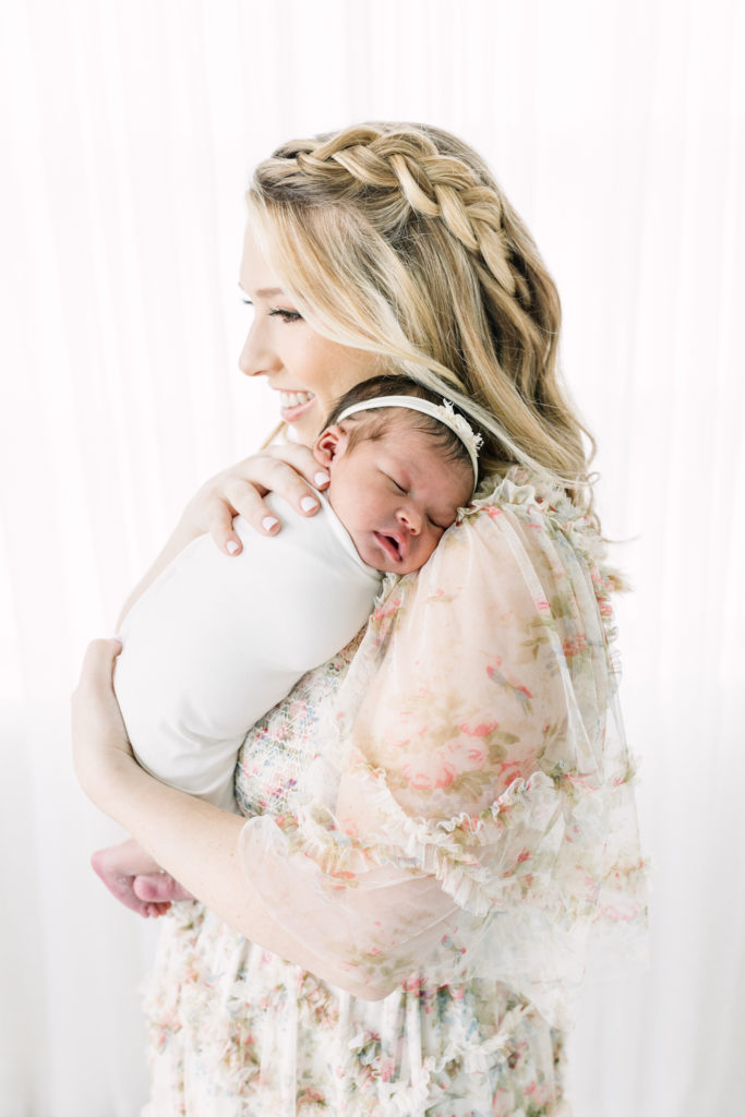 Mom snuggles baby girl during her photoshoot at natural light studio.